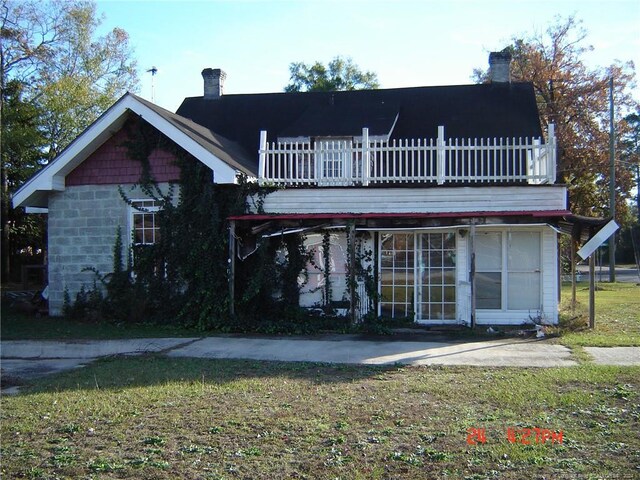 back of property with a balcony and a lawn