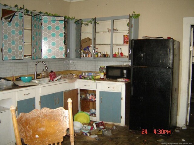 kitchen with backsplash, sink, black appliances, and concrete flooring