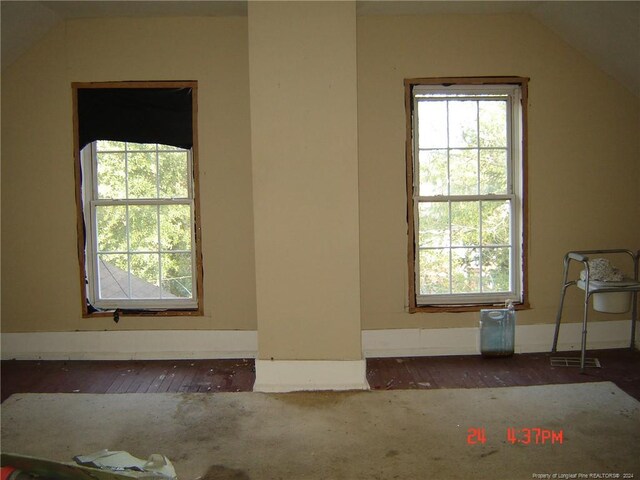 unfurnished room with dark wood-type flooring, a wealth of natural light, and vaulted ceiling