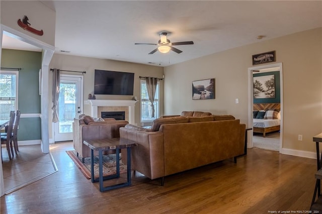 living room featuring dark hardwood / wood-style floors, ceiling fan, and a tile fireplace