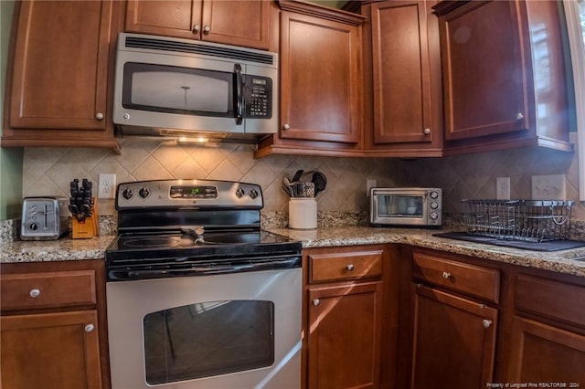 kitchen featuring backsplash, light stone counters, and appliances with stainless steel finishes