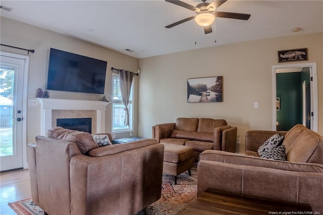 living room featuring ceiling fan, light wood-type flooring, and a fireplace