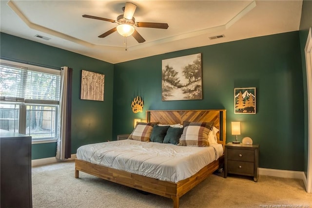 carpeted bedroom featuring a tray ceiling and ceiling fan