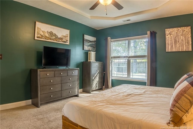 bedroom with a raised ceiling, ceiling fan, and light colored carpet