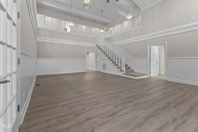 unfurnished living room with a towering ceiling, wood-type flooring, and beamed ceiling