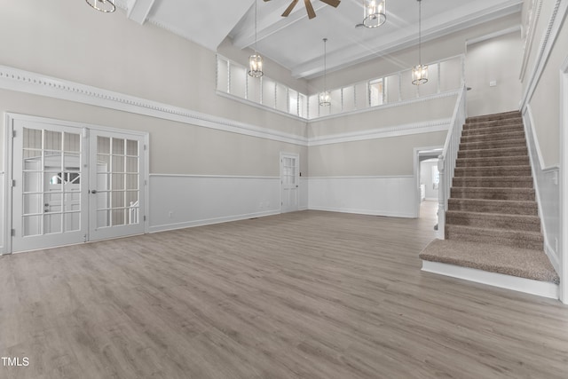 unfurnished living room featuring hardwood / wood-style flooring, french doors, ceiling fan, and beam ceiling