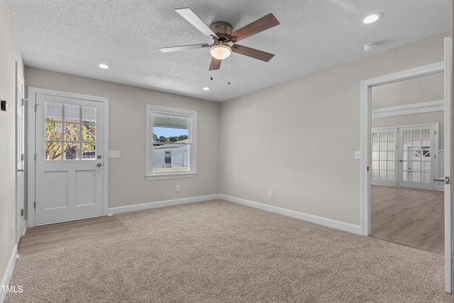 carpeted spare room featuring a textured ceiling and ceiling fan