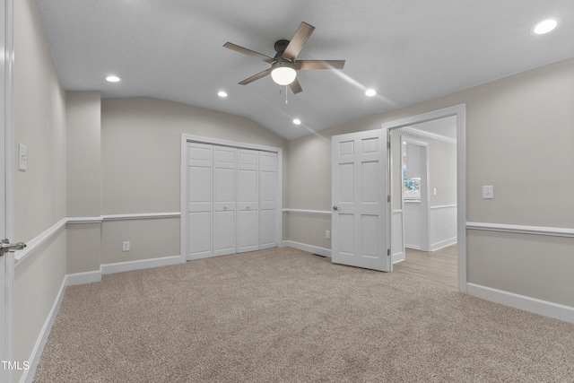 unfurnished bedroom with ceiling fan, light colored carpet, lofted ceiling, and a closet