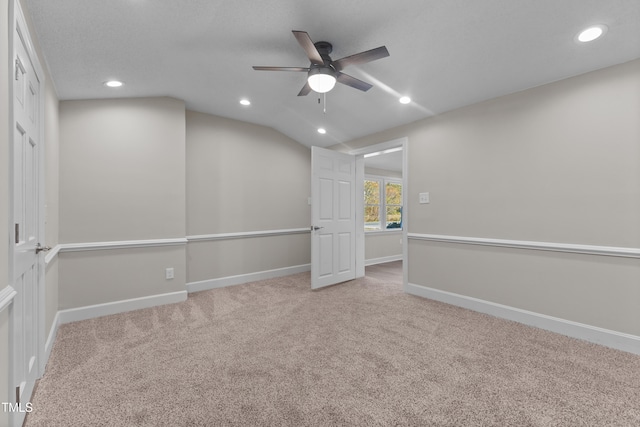 unfurnished room featuring ceiling fan, light colored carpet, lofted ceiling, and a textured ceiling