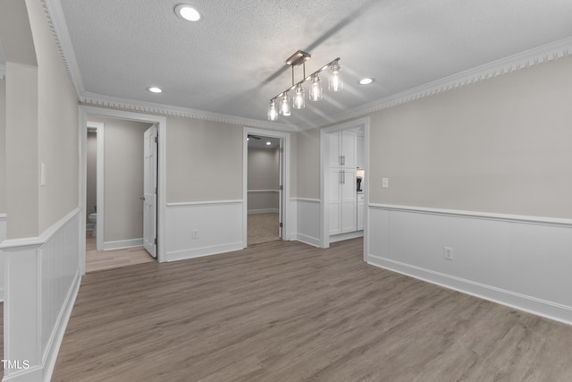 interior space featuring crown molding, light hardwood / wood-style floors, and a textured ceiling