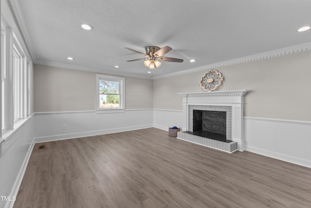 unfurnished living room featuring a fireplace, ornamental molding, ceiling fan, dark wood-type flooring, and a textured ceiling