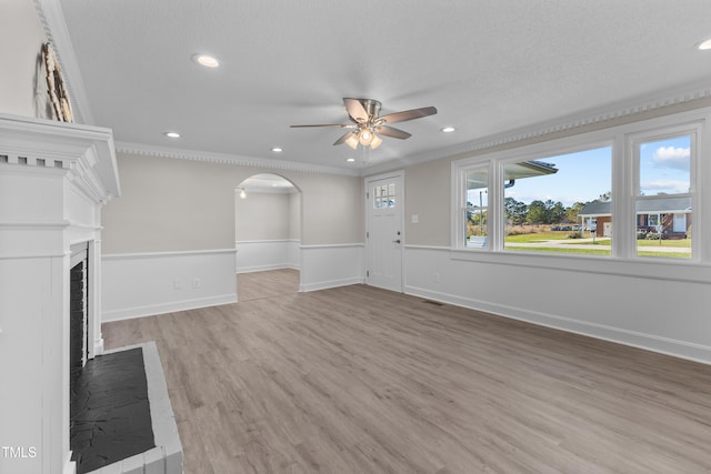 unfurnished living room with crown molding, ceiling fan, hardwood / wood-style floors, and a textured ceiling