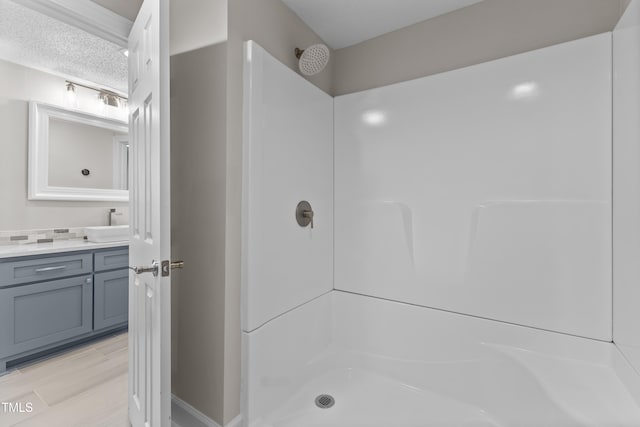 bathroom with vanity, a shower, and a textured ceiling