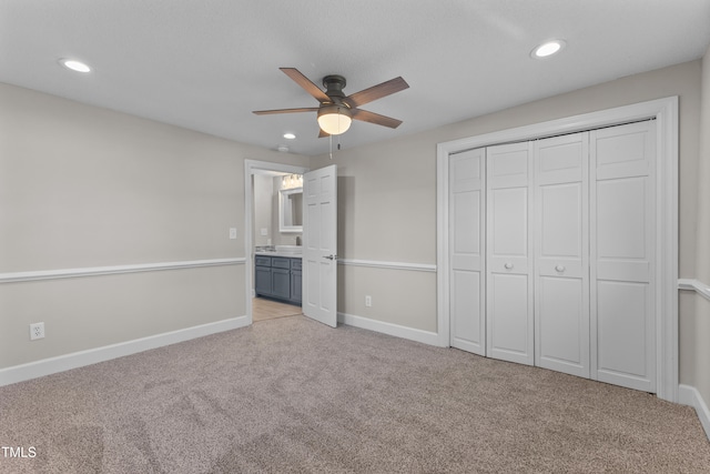 unfurnished bedroom featuring connected bathroom, light carpet, ceiling fan, and a closet