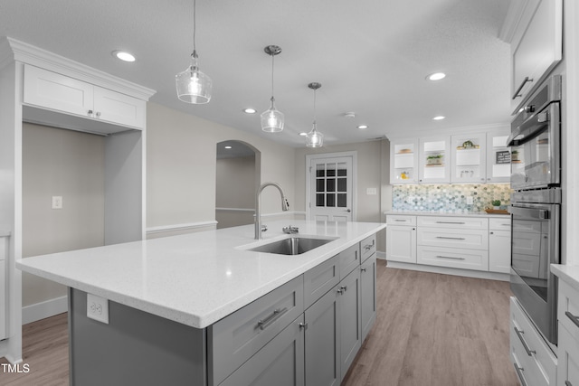 kitchen featuring gray cabinets, white cabinetry, sink, hanging light fixtures, and a center island with sink