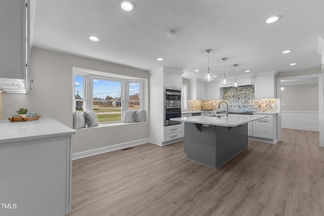 kitchen with stainless steel double oven, hanging light fixtures, backsplash, and white cabinets