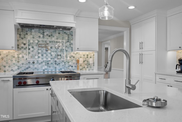 kitchen with stainless steel gas cooktop, sink, hanging light fixtures, and white cabinets