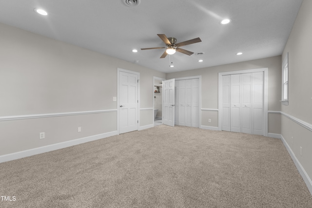 unfurnished bedroom with multiple closets, carpet, and ceiling fan