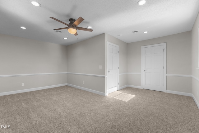 empty room featuring ceiling fan, light carpet, and a textured ceiling