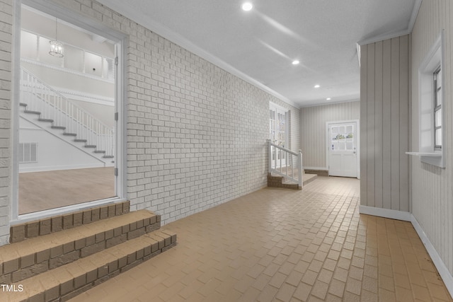 corridor featuring crown molding and brick wall