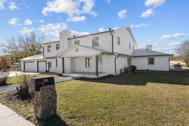 rear view of house with a garage, a lawn, and central air condition unit