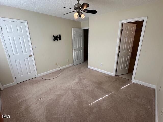 unfurnished bedroom featuring ceiling fan, light carpet, and a textured ceiling