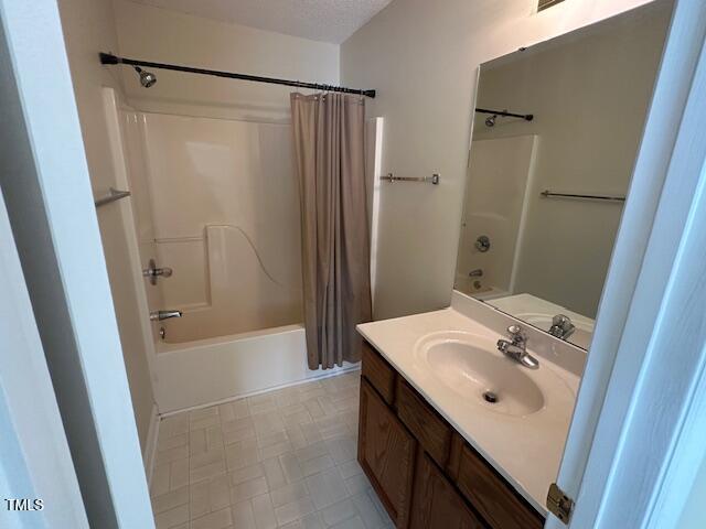 bathroom featuring a textured ceiling, vanity, and shower / tub combo with curtain