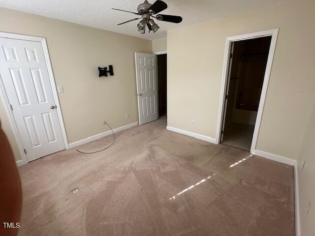 unfurnished bedroom with carpet flooring, ceiling fan, a textured ceiling, and ensuite bath