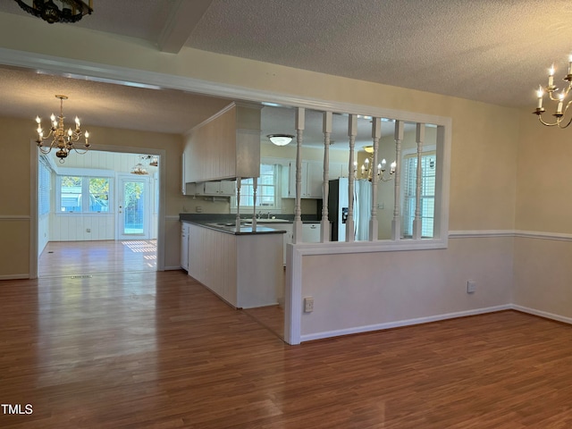 kitchen featuring stainless steel refrigerator, a notable chandelier, hardwood / wood-style floors, a textured ceiling, and decorative light fixtures