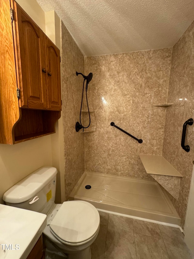 bathroom featuring tile patterned flooring, toilet, a textured ceiling, and a tile shower