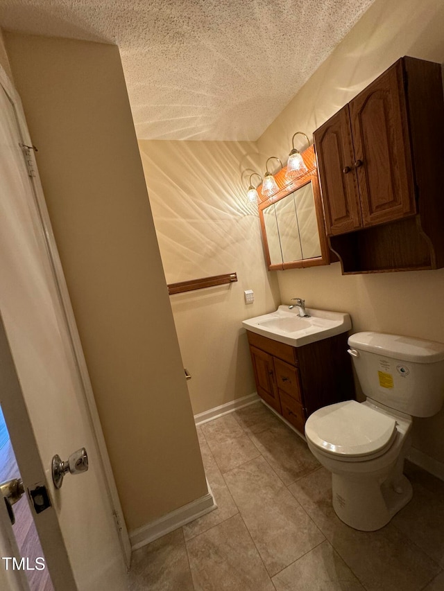 bathroom with tile patterned flooring, vanity, toilet, and a textured ceiling