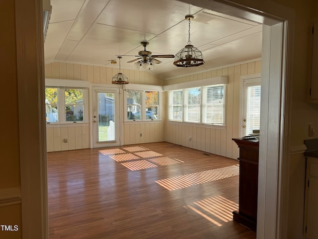 unfurnished sunroom featuring plenty of natural light, ceiling fan with notable chandelier, and vaulted ceiling