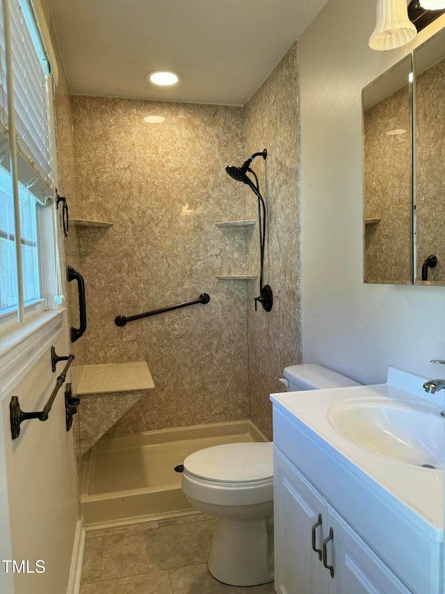 bathroom with tile patterned flooring, vanity, toilet, and tiled shower