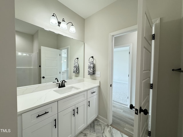 bathroom featuring marble finish floor, vanity, and baseboards