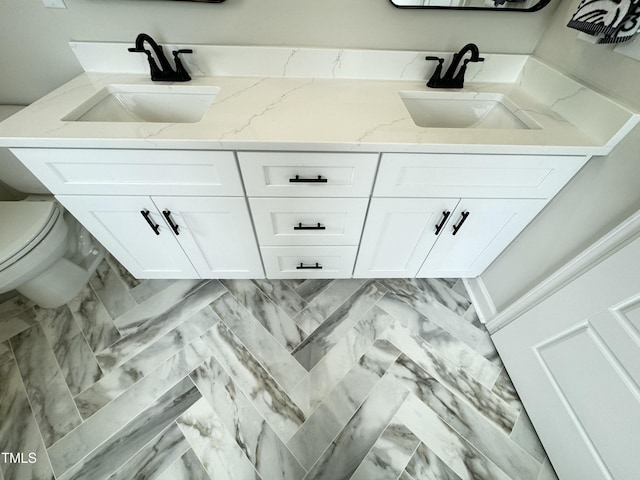 full bathroom with double vanity, toilet, and a sink