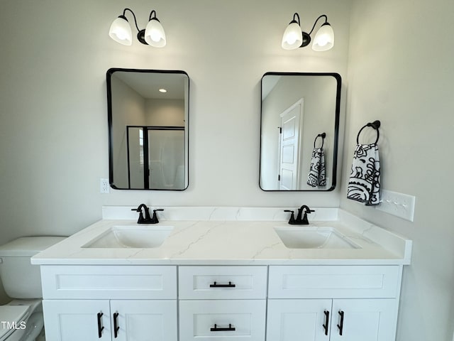 bathroom with a shower stall, toilet, double vanity, and a sink