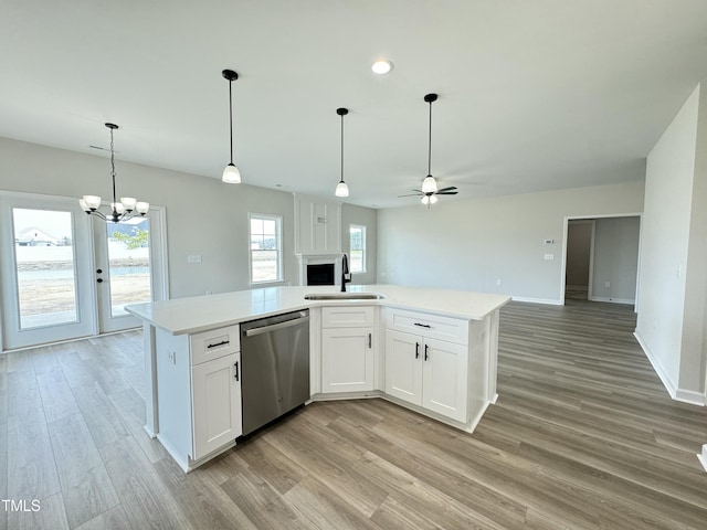 kitchen with a sink, stainless steel dishwasher, open floor plan, and light countertops