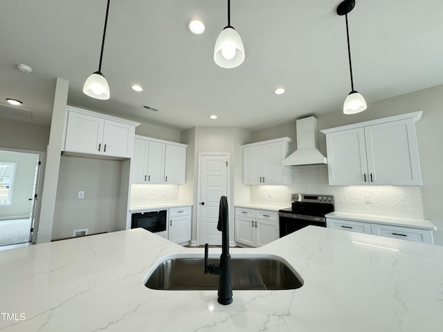 kitchen with pendant lighting, electric stove, a sink, black microwave, and wall chimney range hood