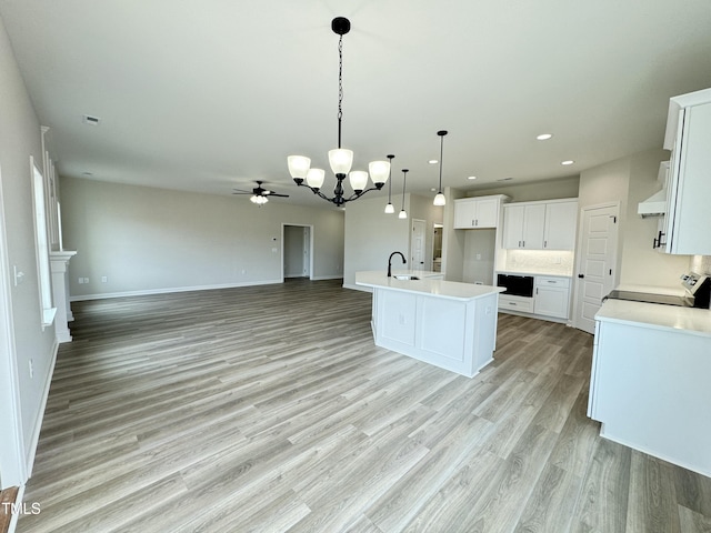 kitchen featuring a sink, open floor plan, light countertops, white cabinets, and range