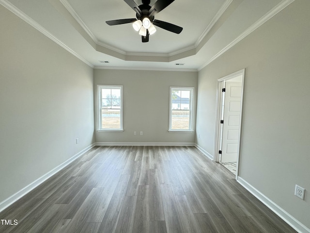 spare room featuring dark wood finished floors, baseboards, crown molding, and a tray ceiling