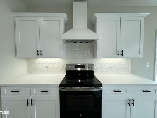 kitchen with black / electric stove, wall chimney exhaust hood, white cabinets, and light stone countertops