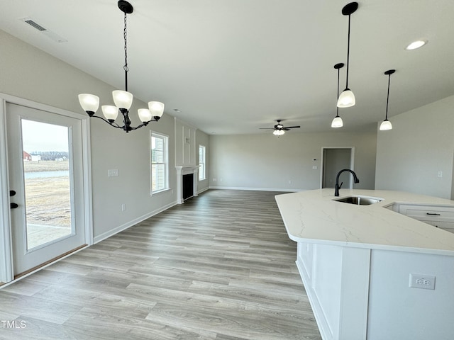 kitchen with visible vents, a fireplace, light wood-type flooring, and a sink