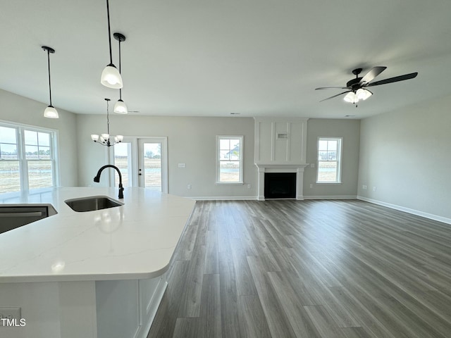 kitchen with wood finished floors, light stone countertops, a fireplace, a sink, and open floor plan