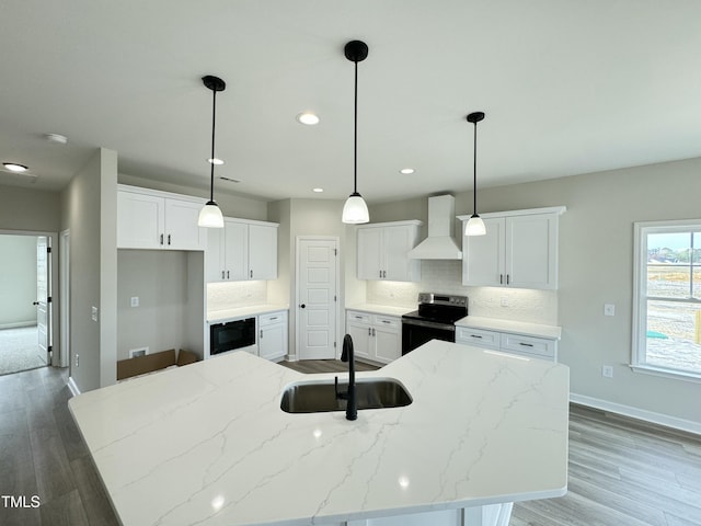 kitchen featuring premium range hood, range with electric cooktop, a center island with sink, a sink, and black microwave