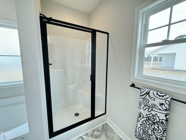 full bath with a shower stall, marble finish floor, and baseboards