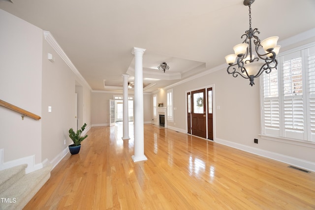 foyer featuring decorative columns, a chandelier, ornamental molding, and hardwood / wood-style flooring