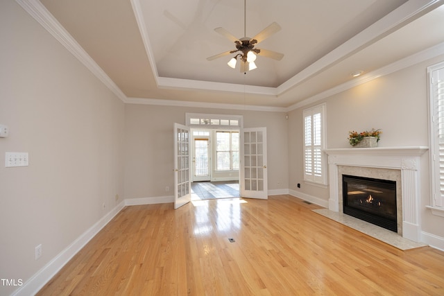 unfurnished living room with a high end fireplace, french doors, ceiling fan, light wood-type flooring, and ornamental molding