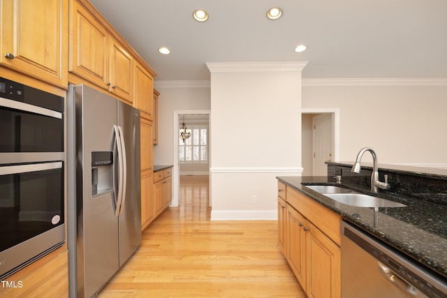 kitchen with dark stone counters, stainless steel appliances, sink, an inviting chandelier, and light hardwood / wood-style floors