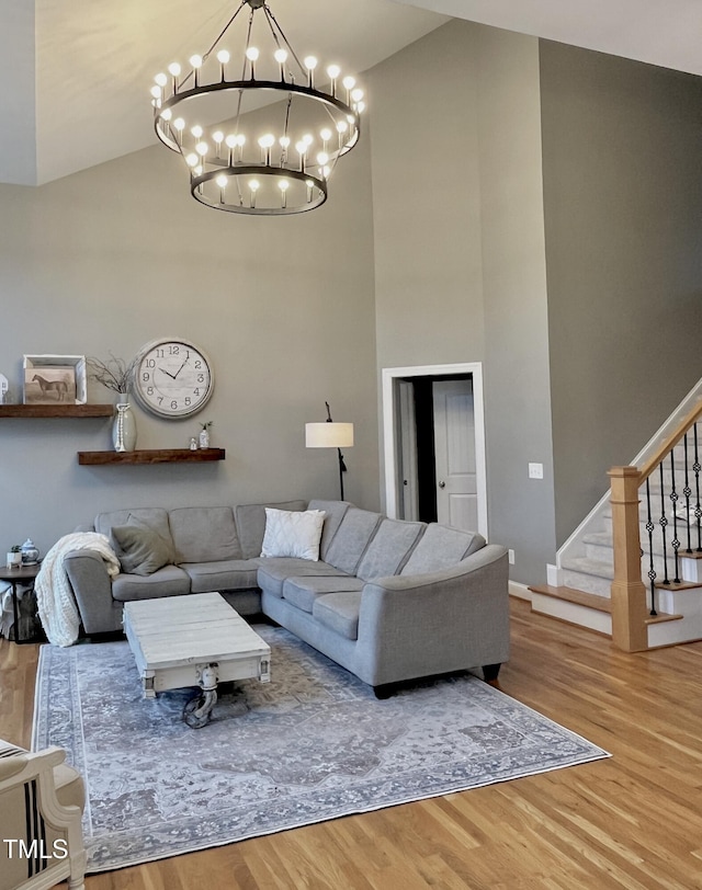 living room with hardwood / wood-style flooring, high vaulted ceiling, and a chandelier