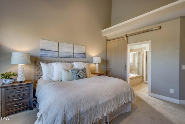 bedroom featuring a barn door, light colored carpet, and ensuite bath